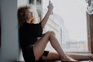 woman in black dress sitting on window