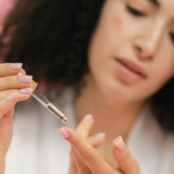 close up of woman putting serum on her finger with the use of a pipette