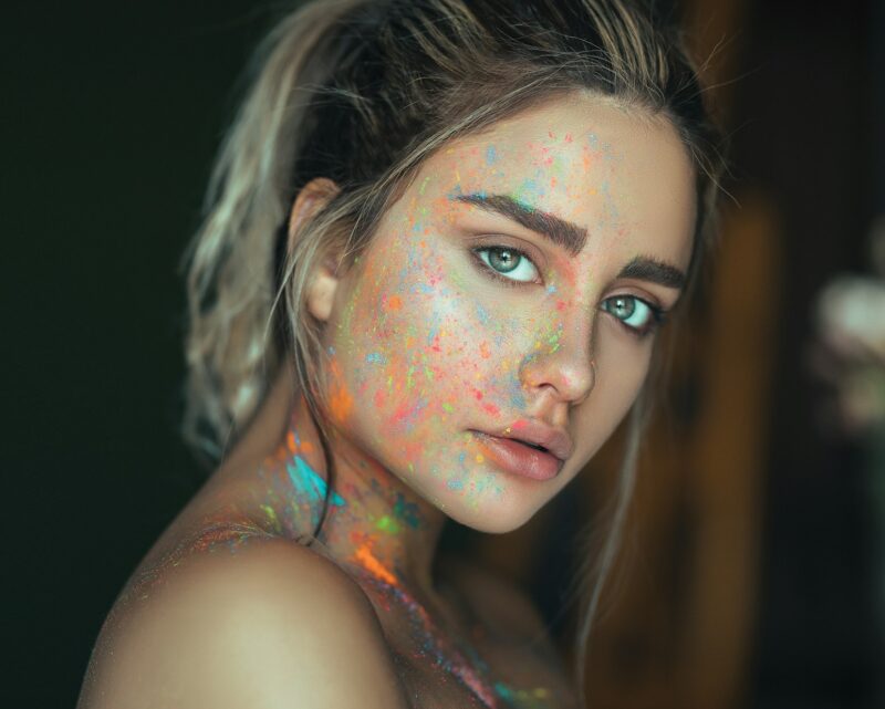 mujer joven con clean look y pintura fluorescente salpicada en la cara