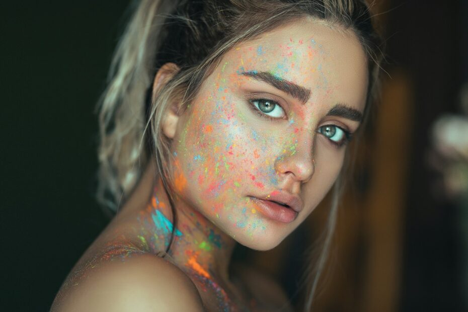 mujer joven con clean look y pintura fluorescente salpicada en la cara