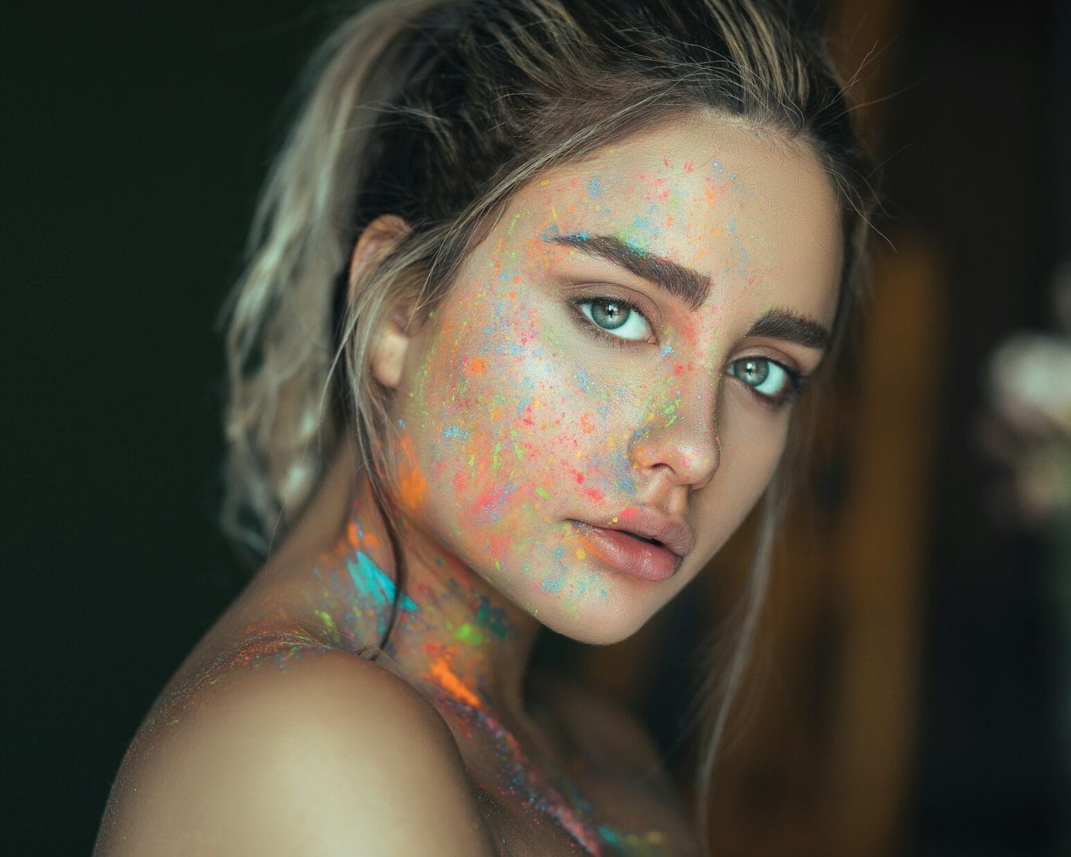 mujer joven con clean look y pintura fluorescente salpicada en la cara